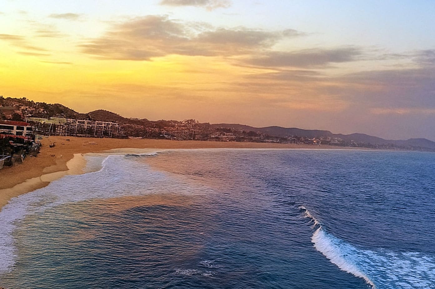 Costa Azul beach track at sunset with surfers and glowing horizon