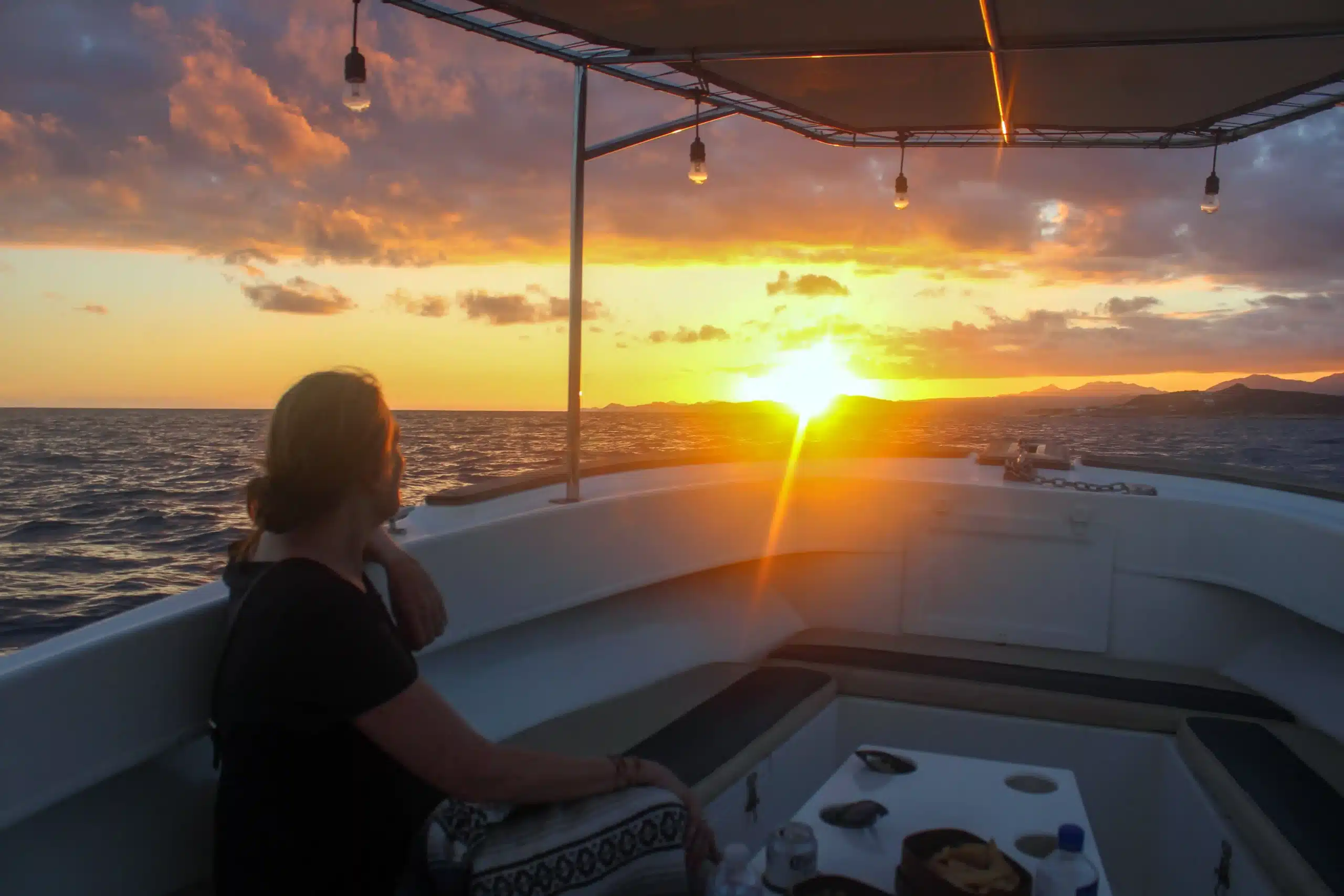 Guests watching the sun dip beyond the horizon aboard a yacht in San Jos&eacute; del Cabo