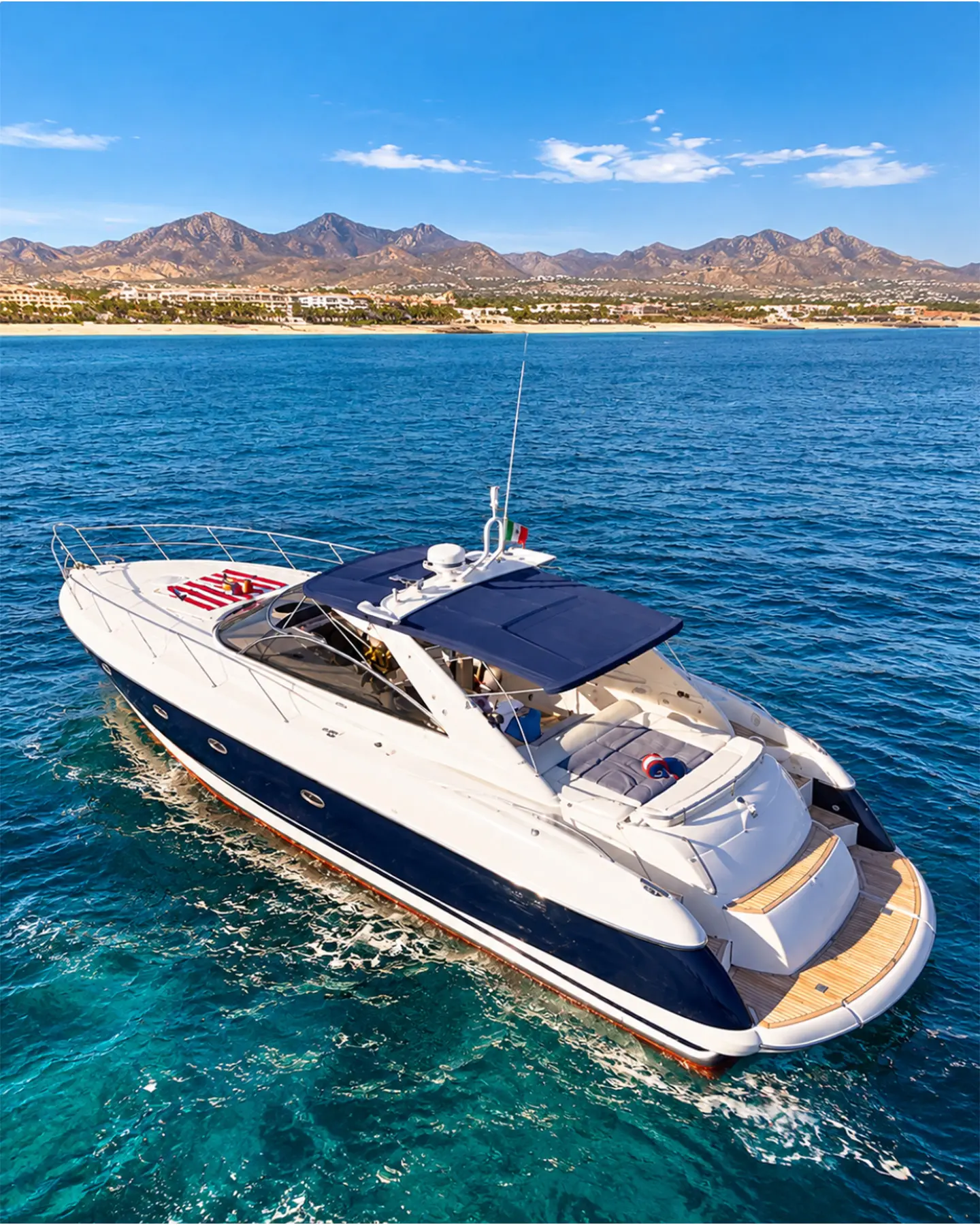 Luxury Sunseeker yacht cruising through the turquoise waters of the Sea of Cortez, with the beautiful coastline and mountains of San José del Cabo in the background.